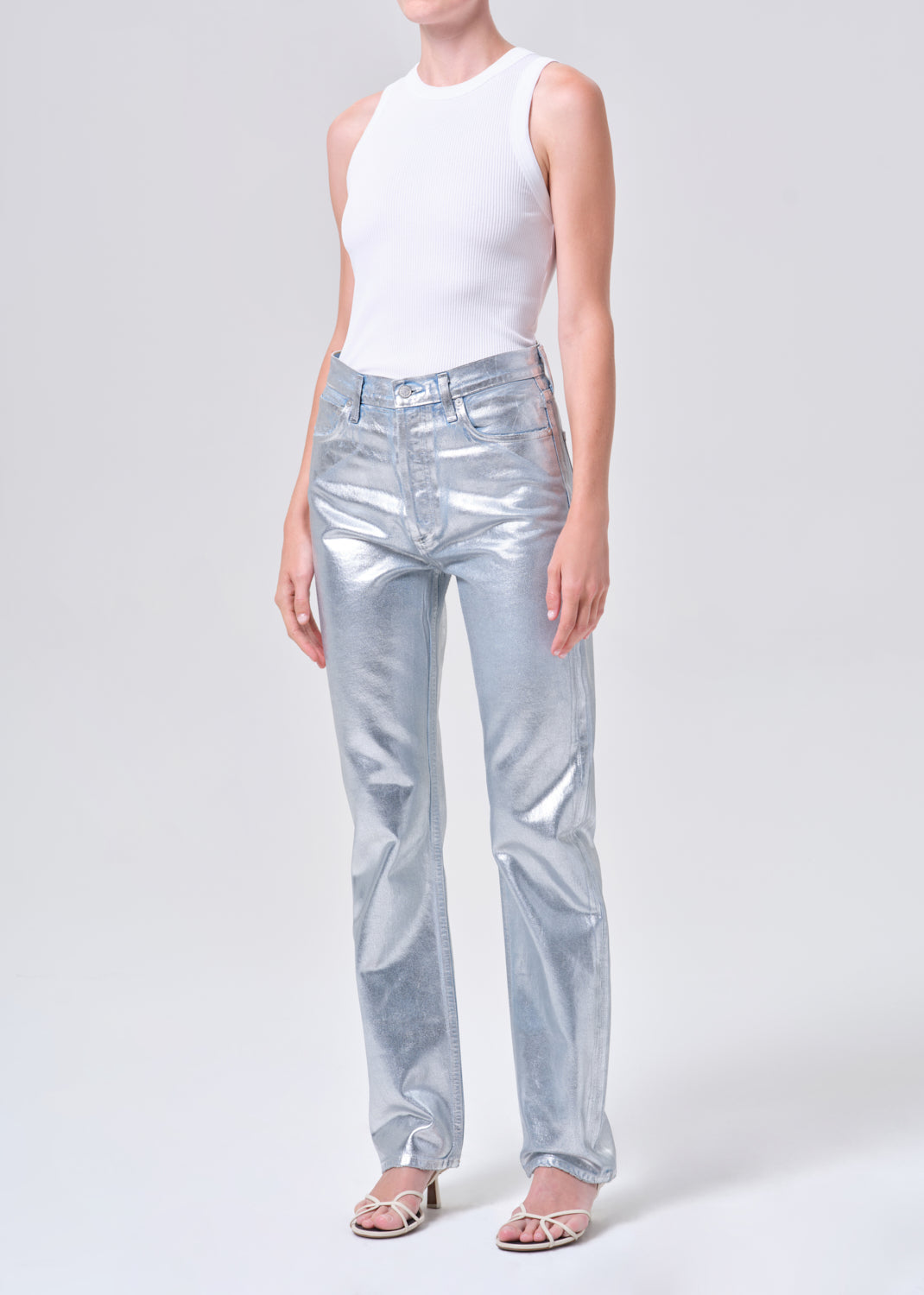 Person wearing light blue jeans and a white top on a white background