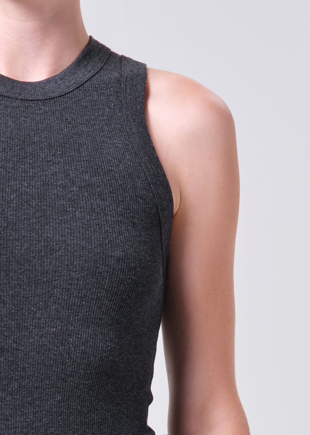 Dark gray sleeveless top worn by a person on a light gray background