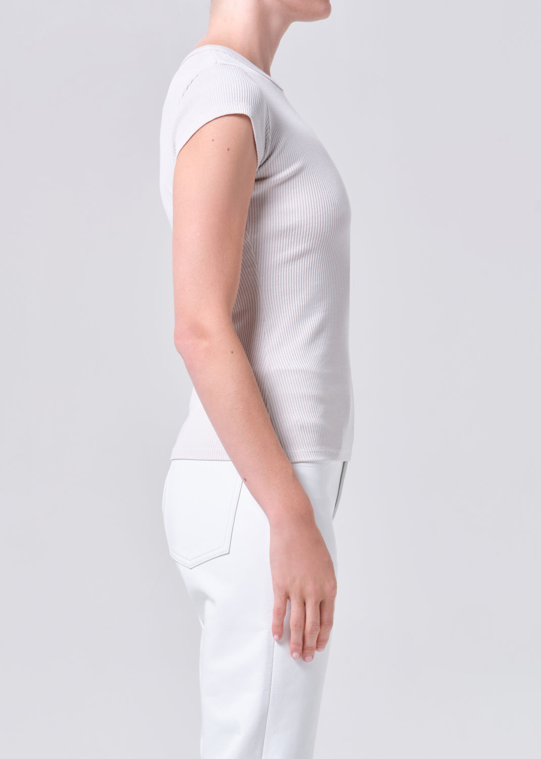 Person wearing a light gray top and white pants on a plain background