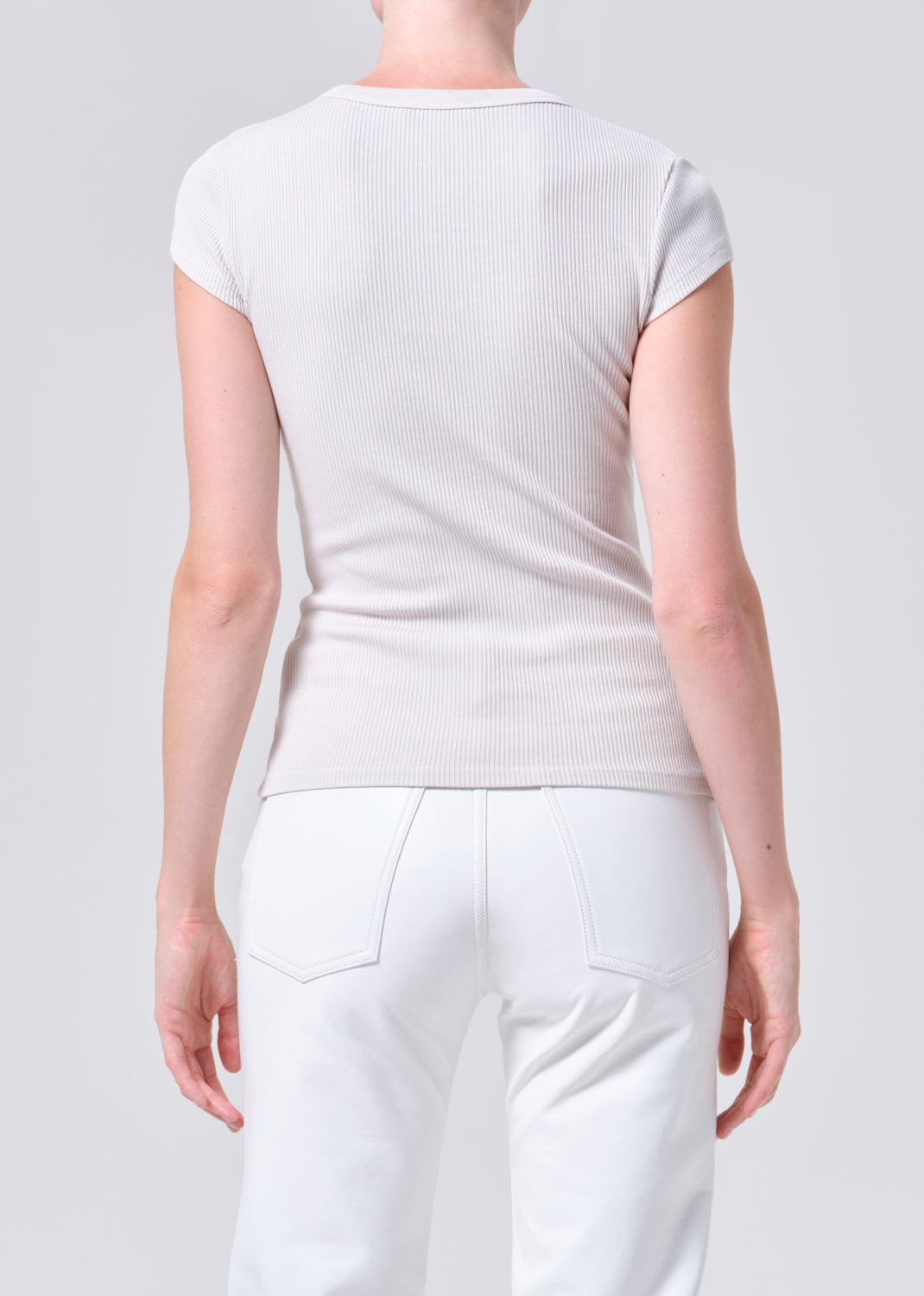 Person wearing a plain white t-shirt and pants on a light gray background