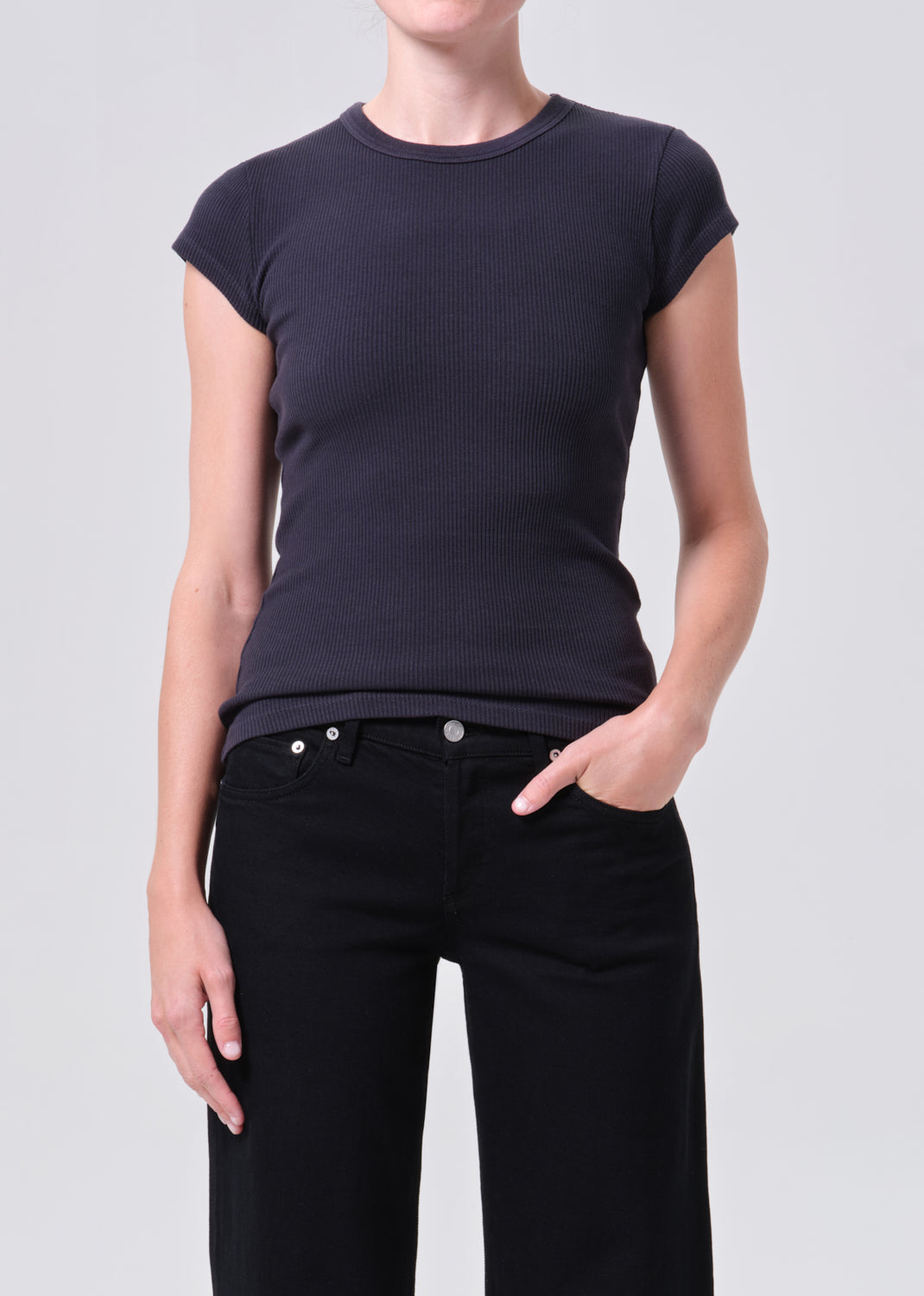 Person wearing a black t-shirt and black pants on a light gray background