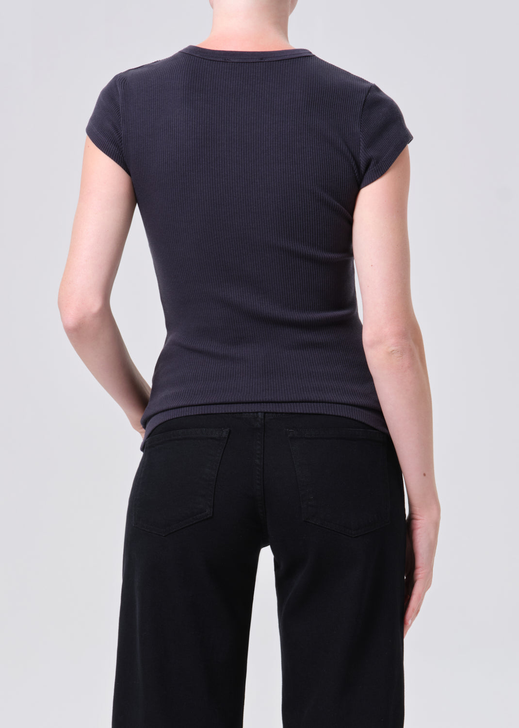 Person wearing a black t-shirt and black pants on a light gray background