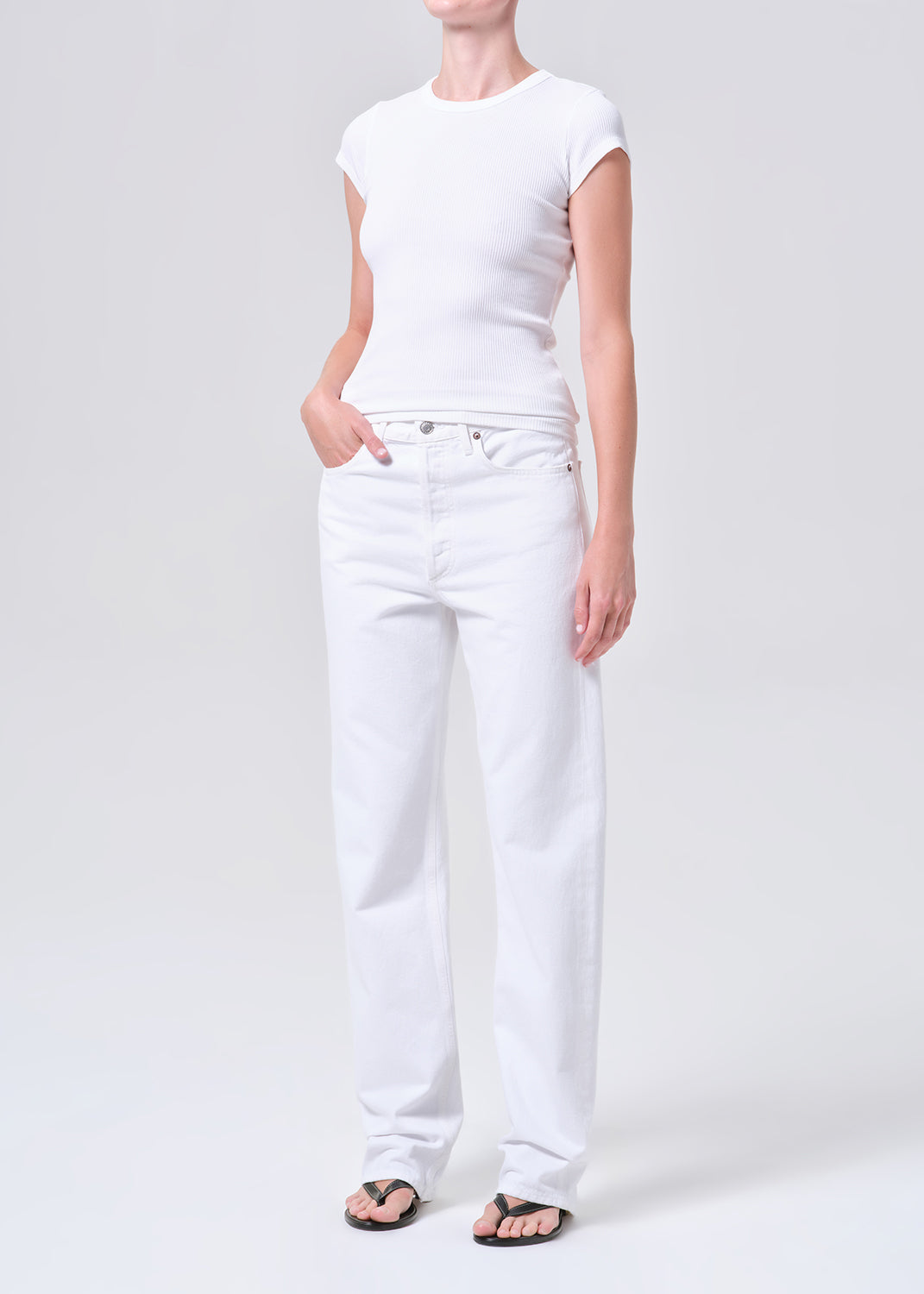 Person wearing a white t-shirt and white pants on a plain background