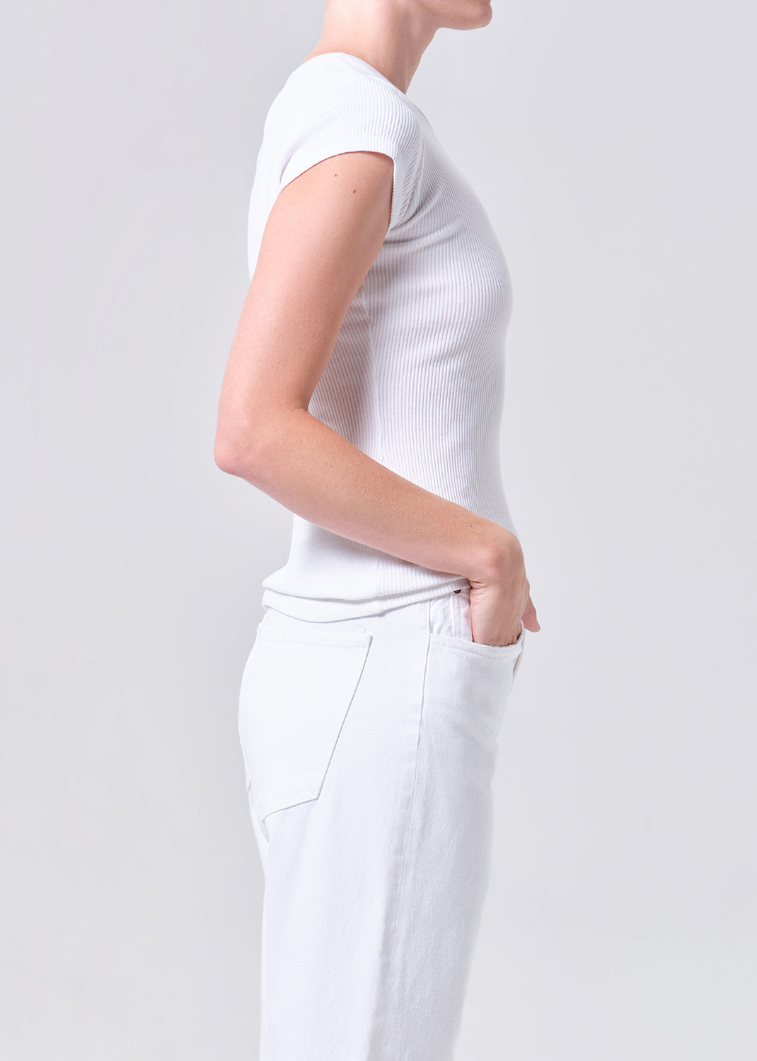 Person wearing a plain white t-shirt and pants on a light gray background