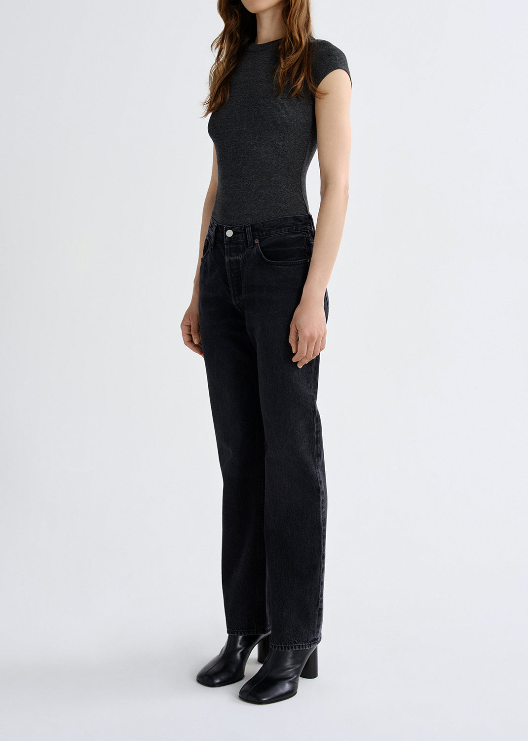 Person wearing a black sleeveless top and black jeans on a white background