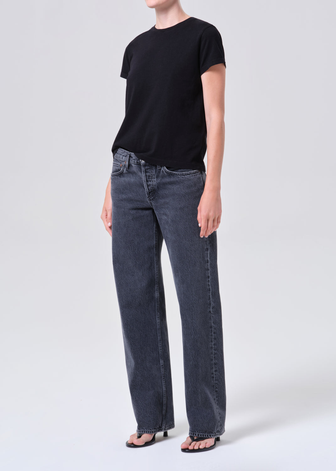 Person wearing a black t-shirt and dark blue jeans on a white background