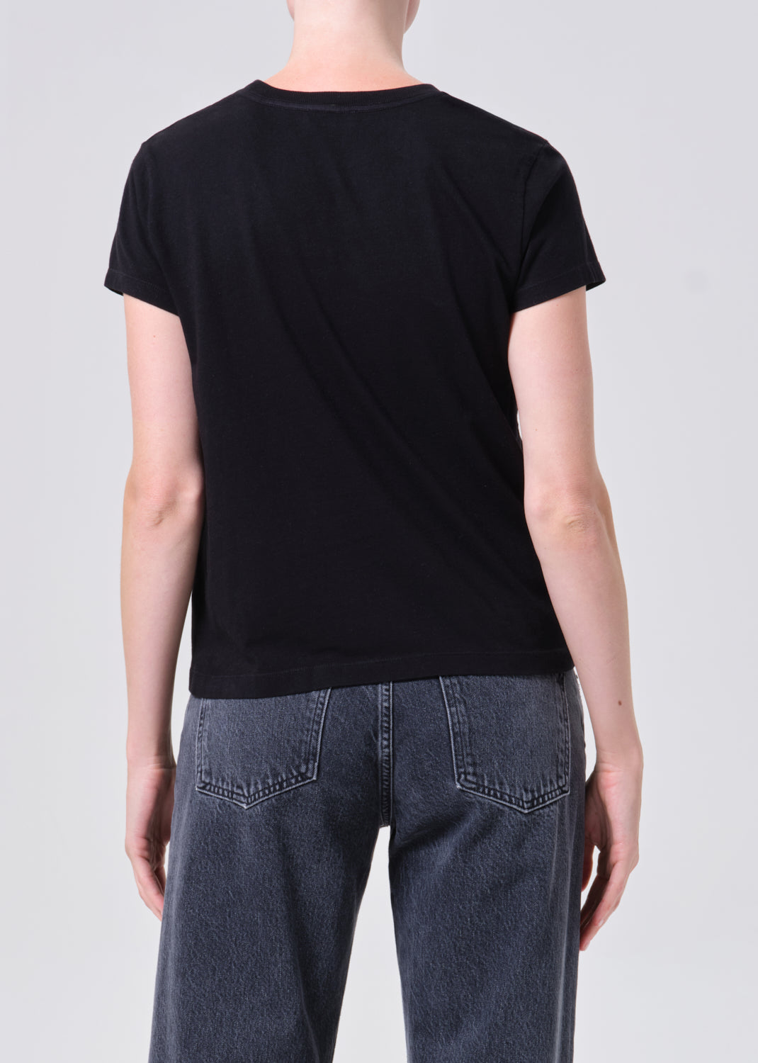 Person wearing a black t-shirt and blue jeans on a white background