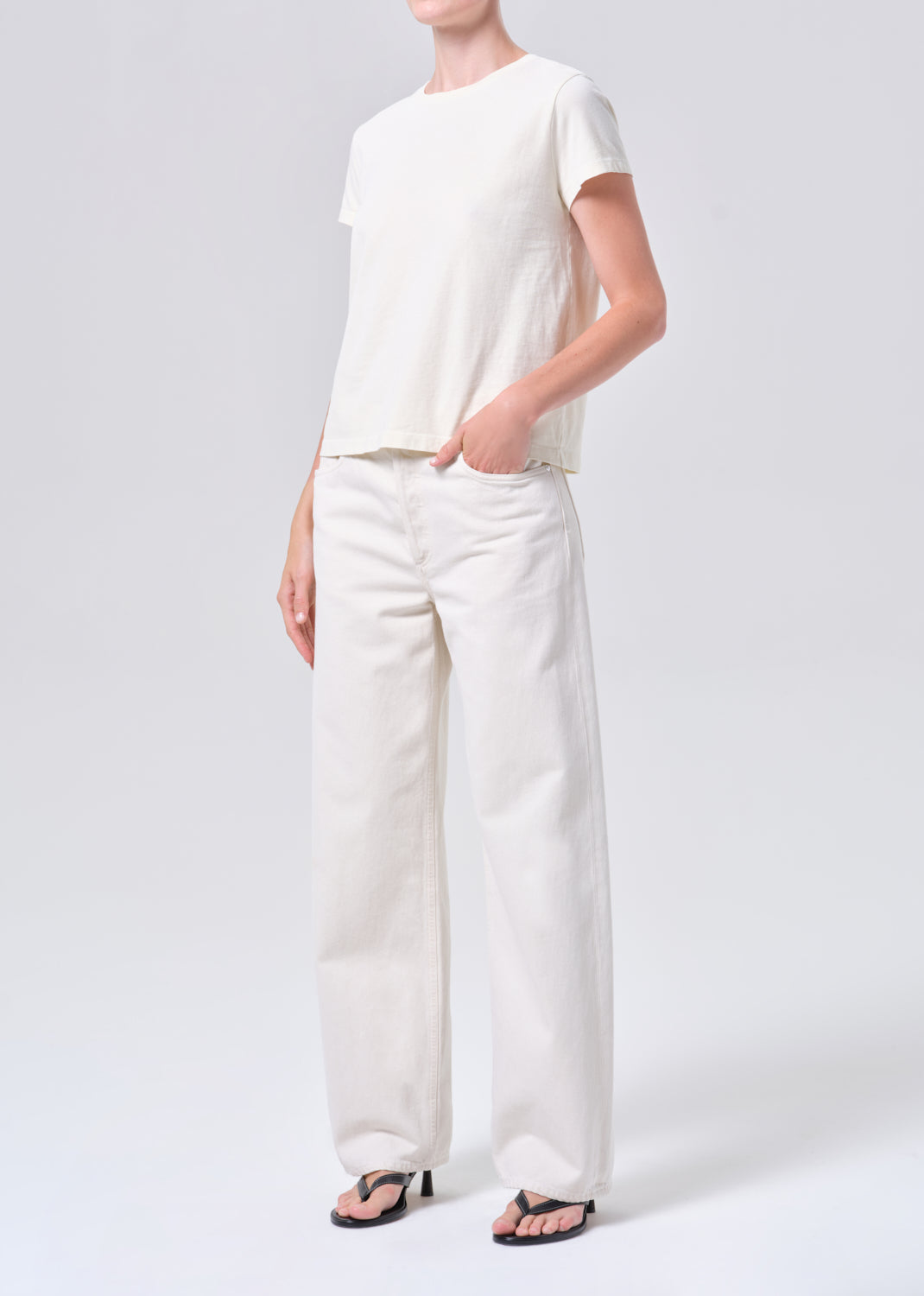 Person wearing a white t-shirt and pants on a plain background