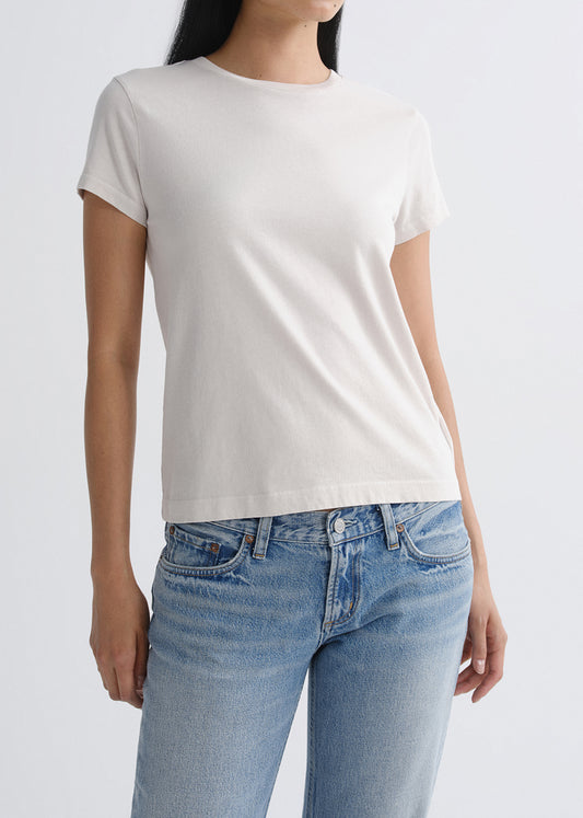 Person wearing a plain white t-shirt and blue jeans on a grey background