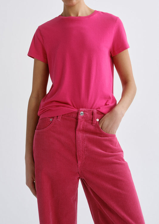 Person wearing a bright pink short sleeve crewneck tee with bright pink straight leg jeans on a grey background