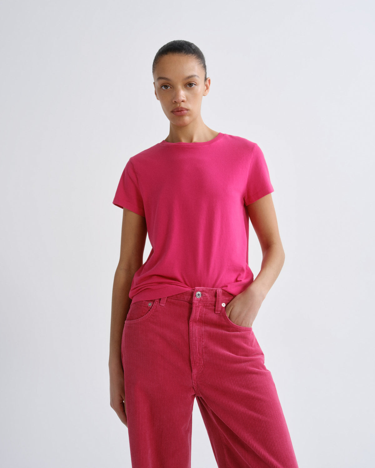 Person wearing a bright pink t-shirt and pants on a white background