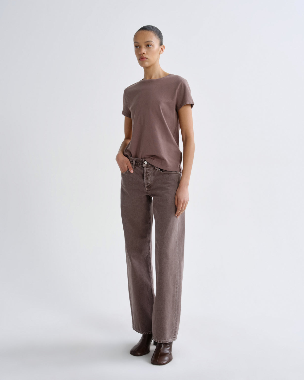 Person wearing a brown t-shirt and pants on a white background