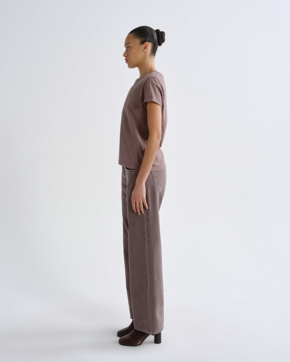 Woman wearing a brown outfit standing against a white background