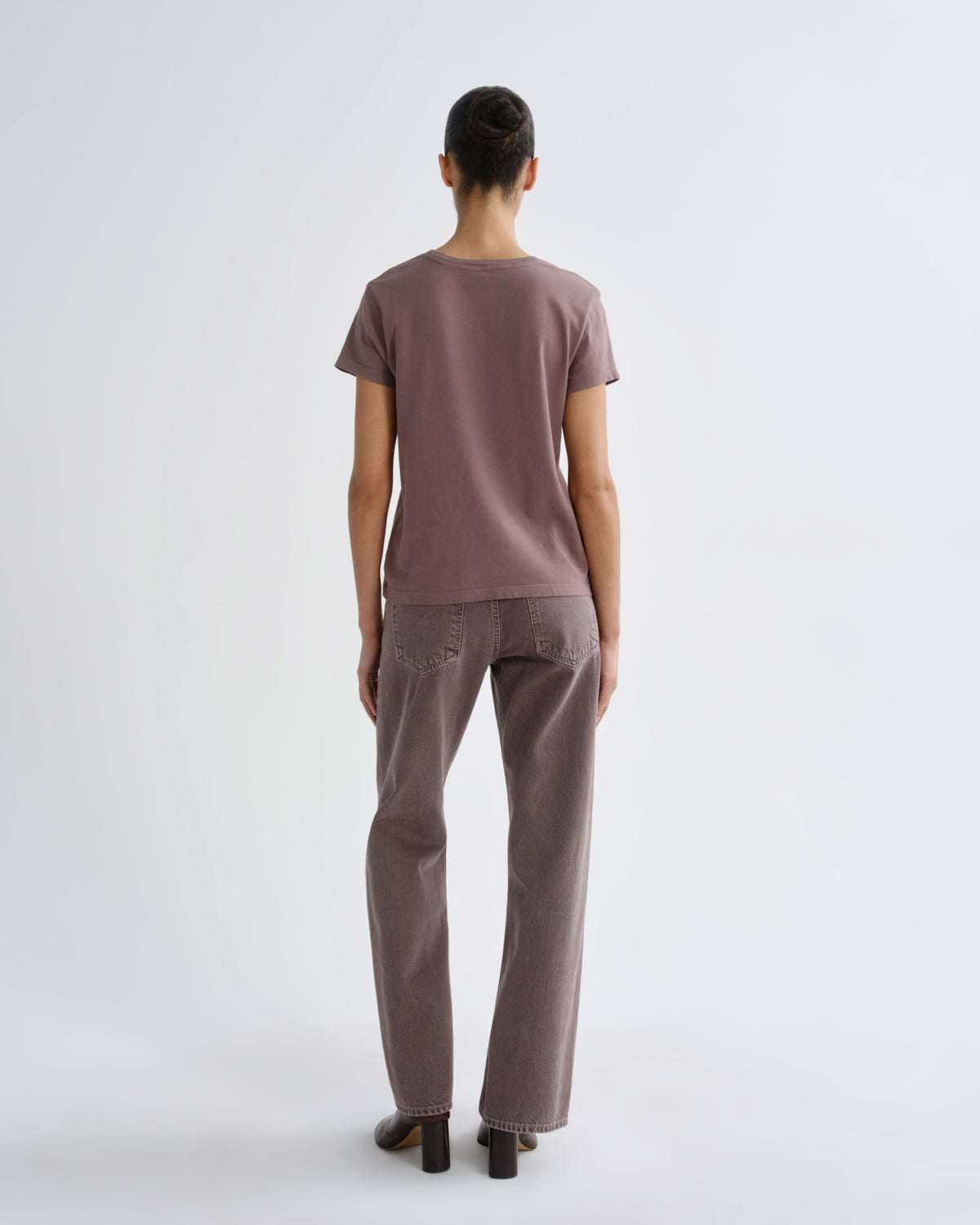 Person wearing a brown t-shirt and pants on a white background