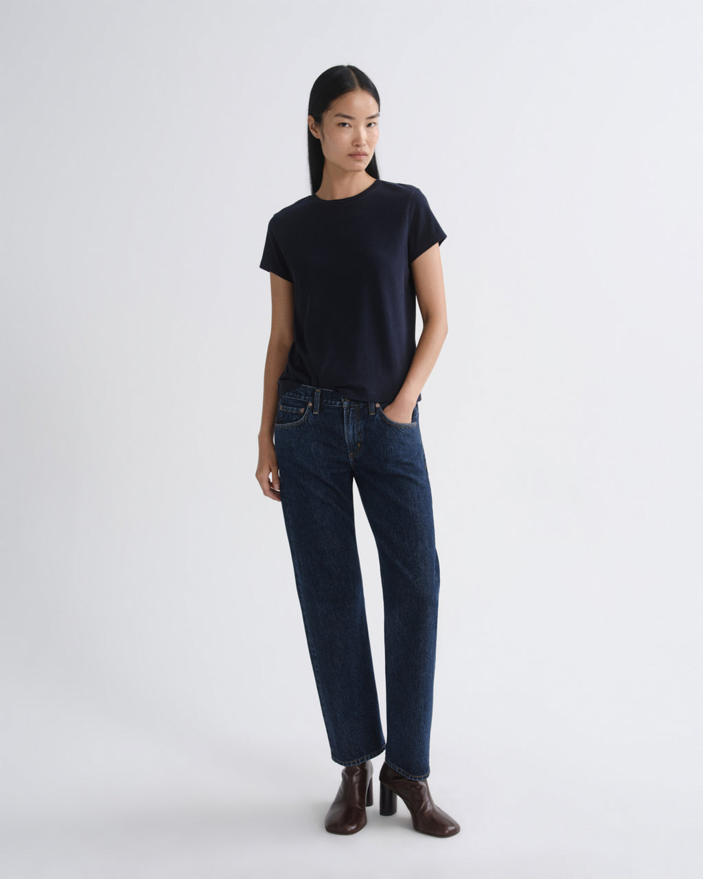 Woman wearing a black t-shirt and dark blue jeans on a white background