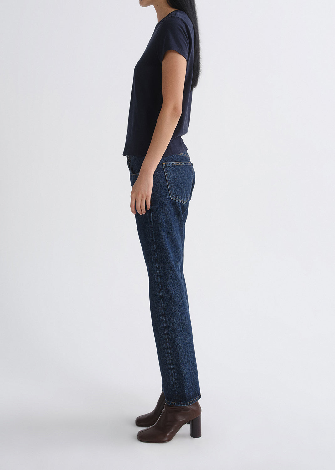 Person wearing a navy t-shirt and blue jeans on a grey background