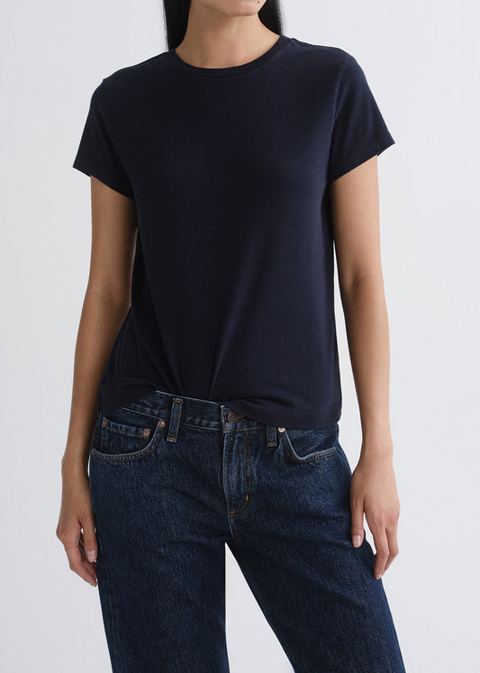 Person wearing a black t-shirt and blue jeans on a grey background