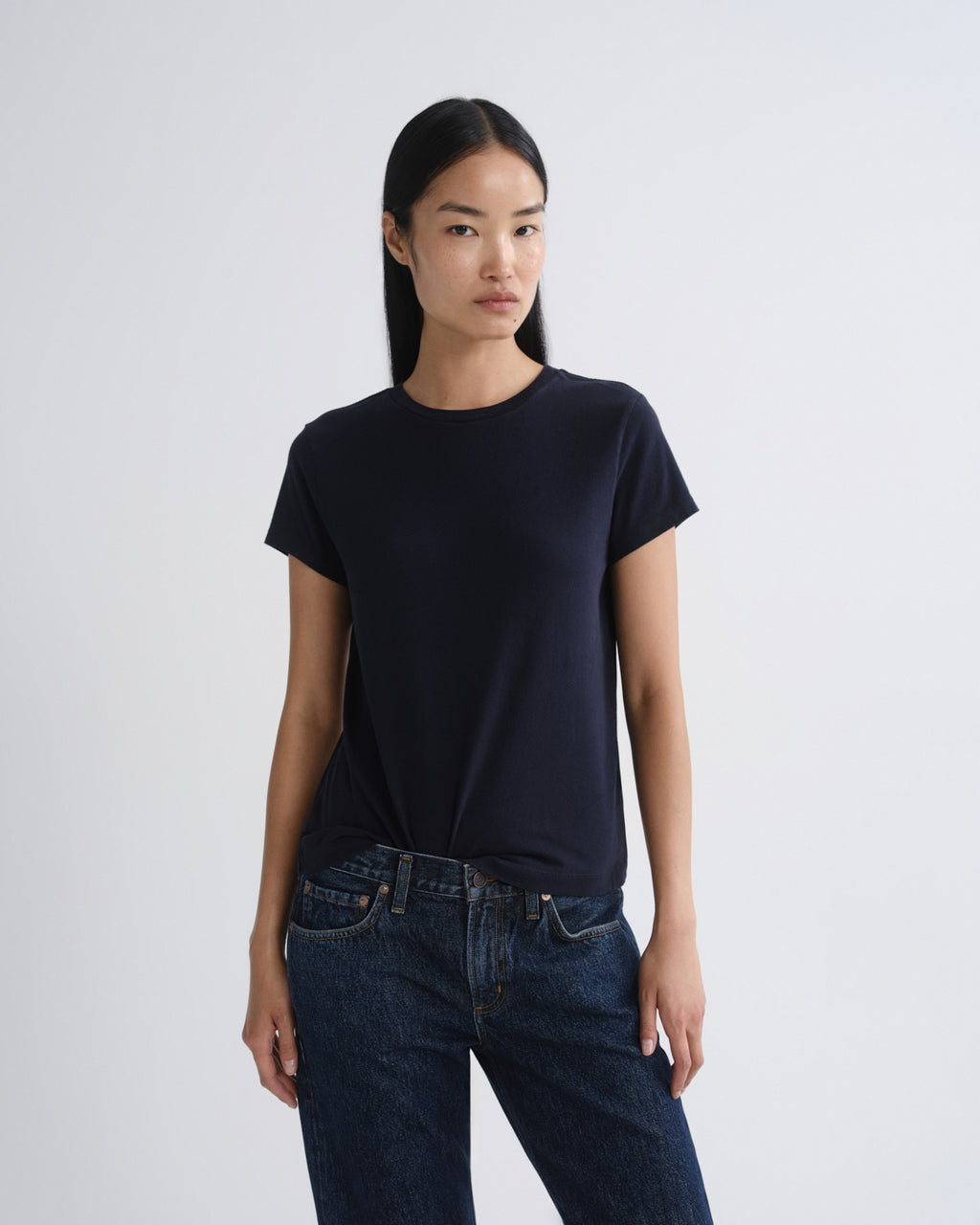 Person wearing a black t-shirt and dark jeans on a white background