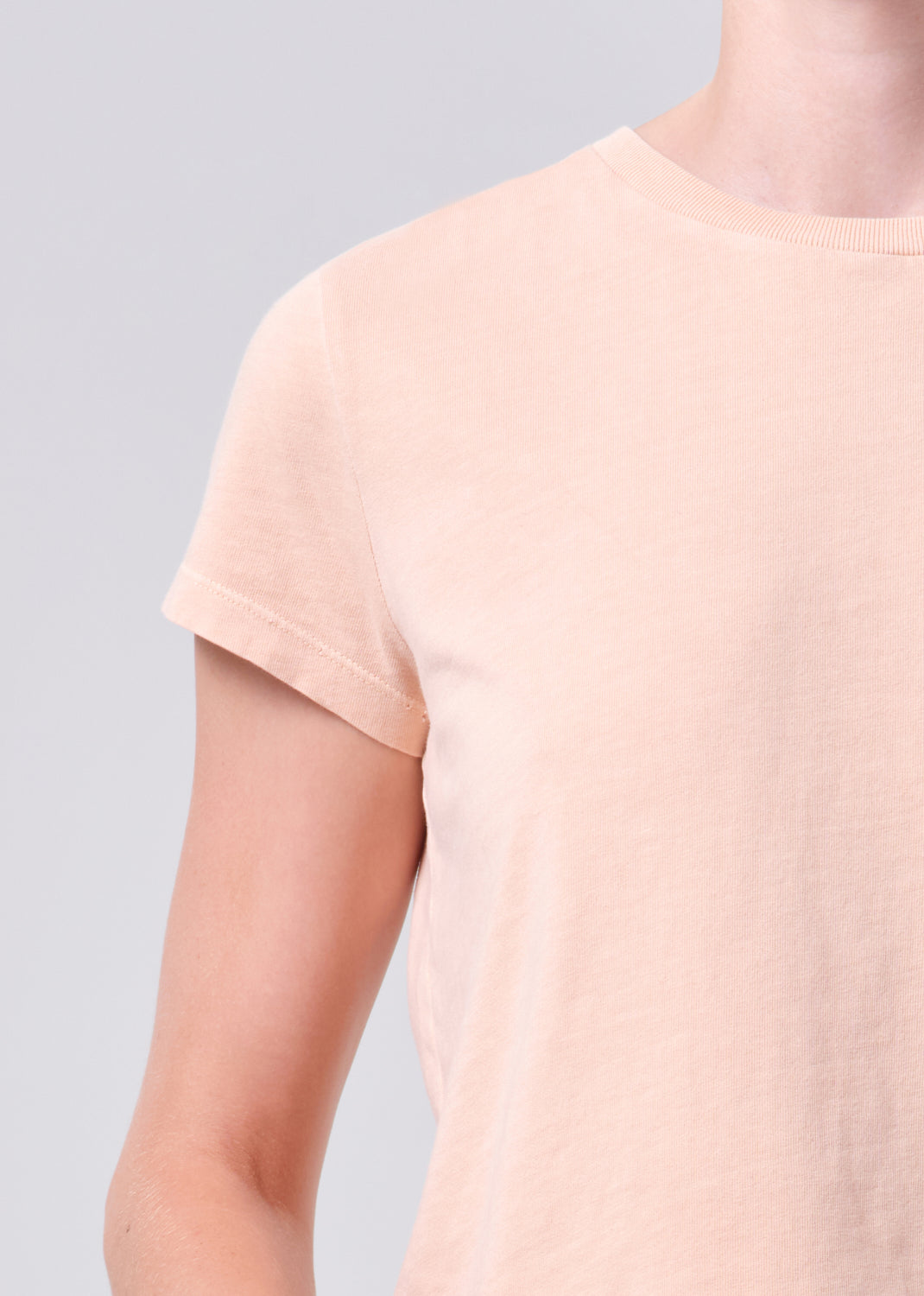 Person wearing a light pink t-shirt against a gray background