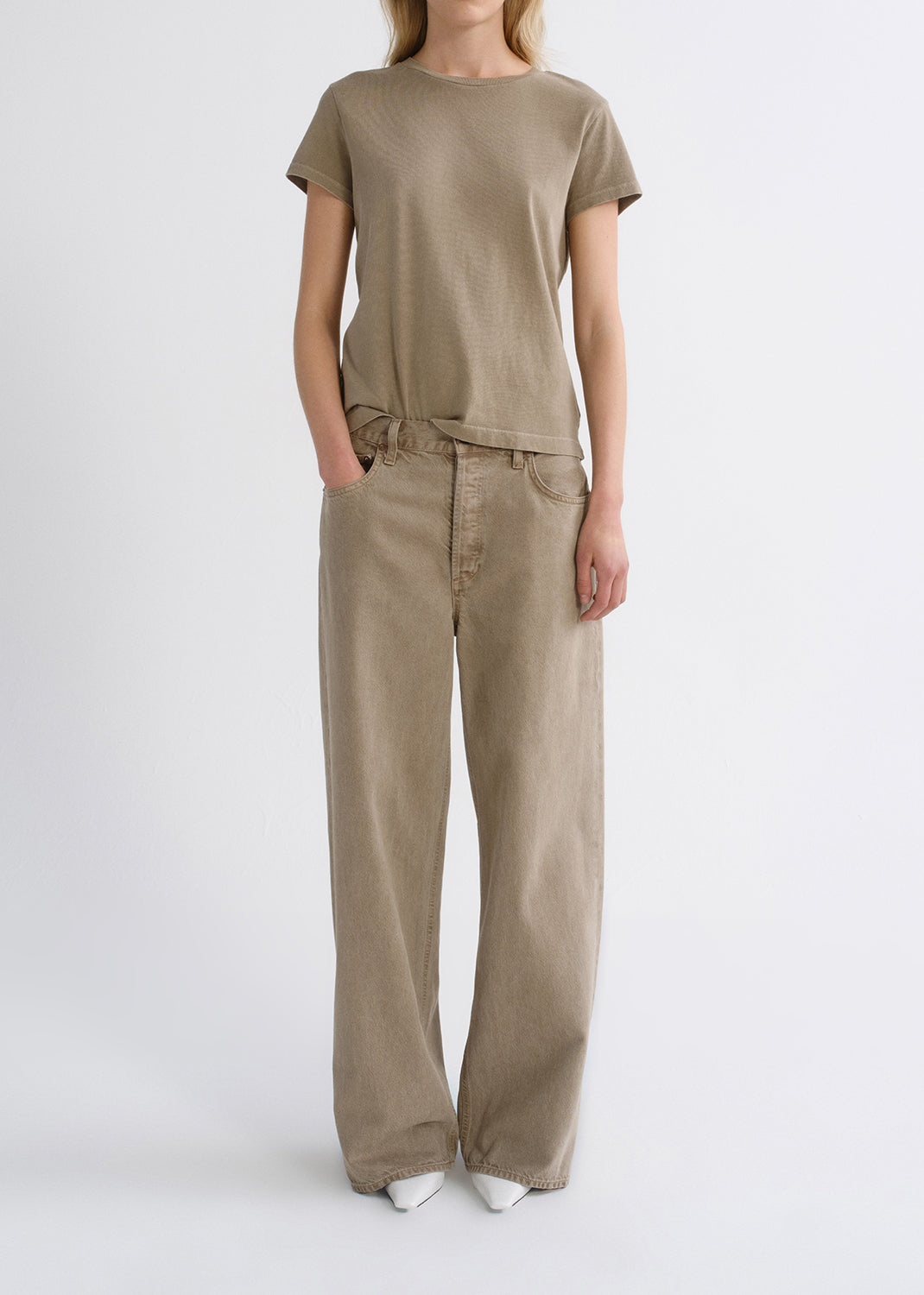 Person wearing a tan outfit on a grey background