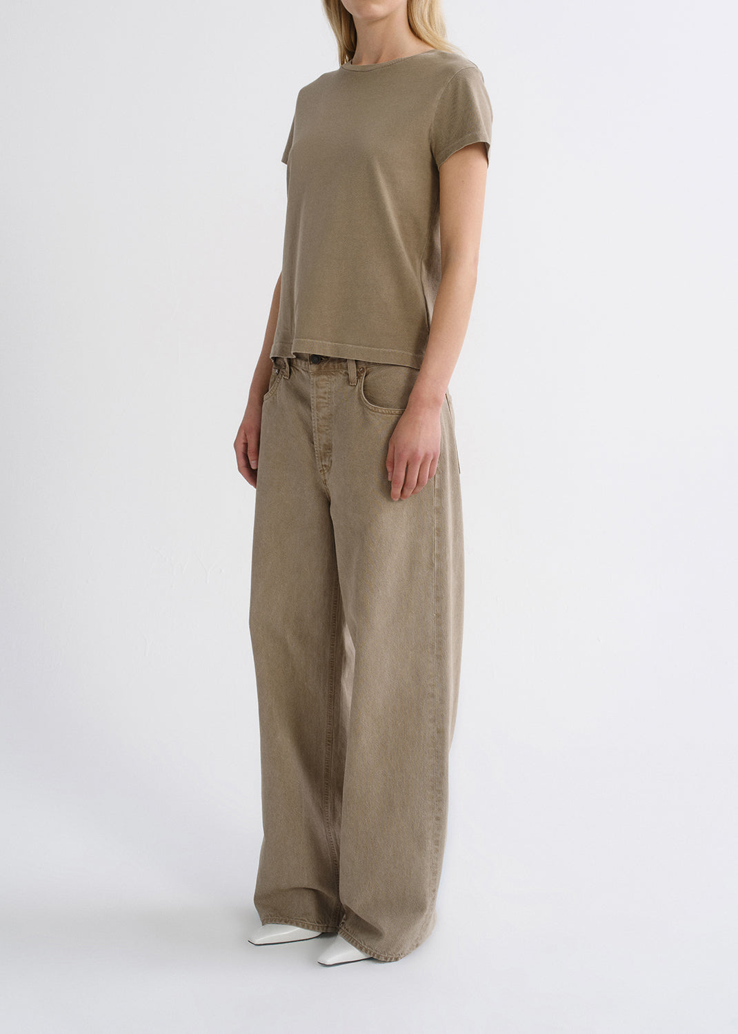 Person wearing a tan outfit on a grey background