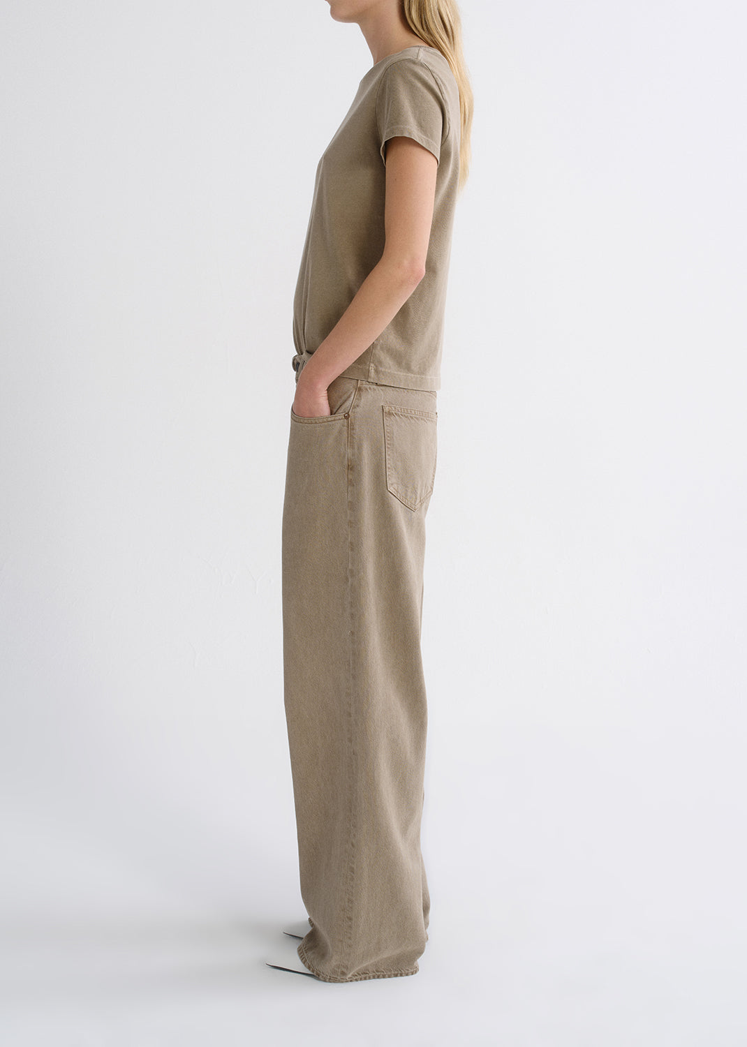 Person wearing a tan outfit on a grey background