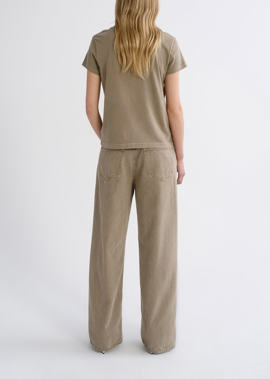 Person wearing a tan outfit on a grey background