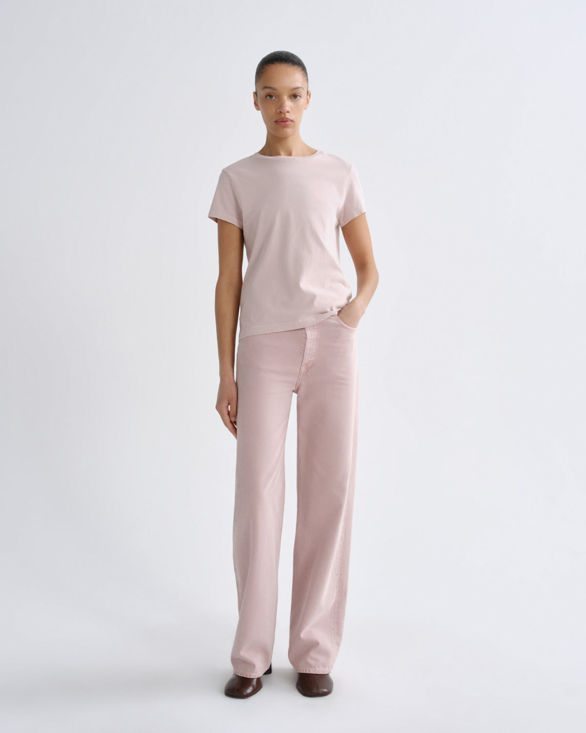 Person wearing a light pink t-shirt and pants on a white background