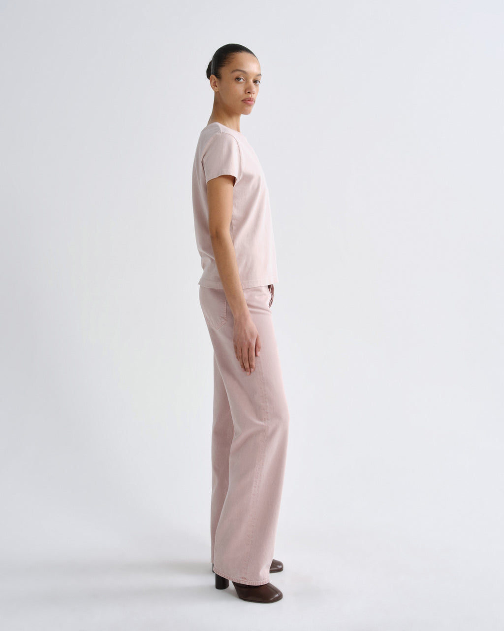 Person wearing a light pink outfit on a white background