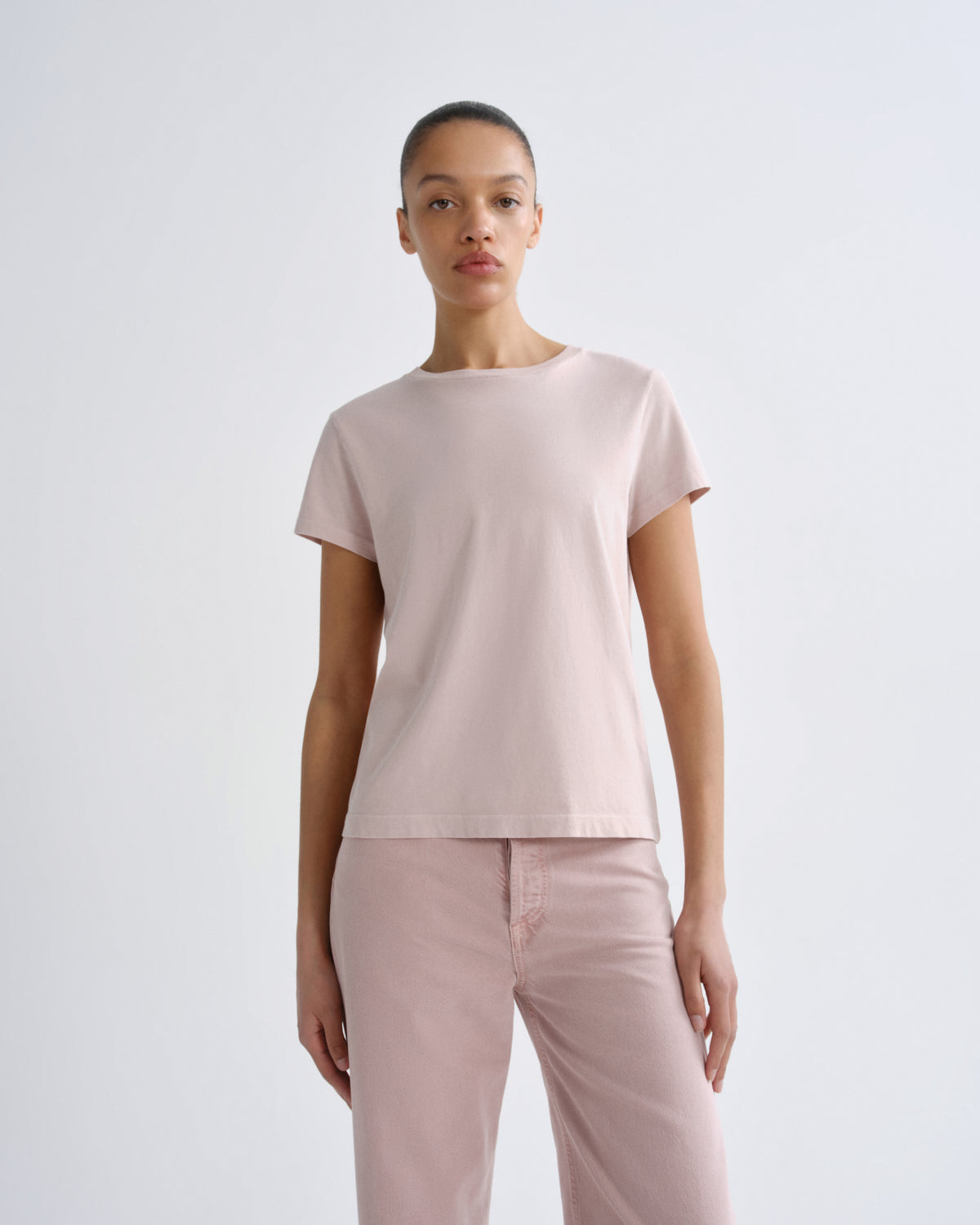 Woman wearing a light pink top and pants on a white background