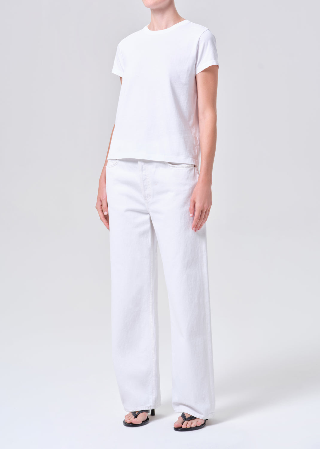 Person wearing a white t-shirt and pants on a plain background