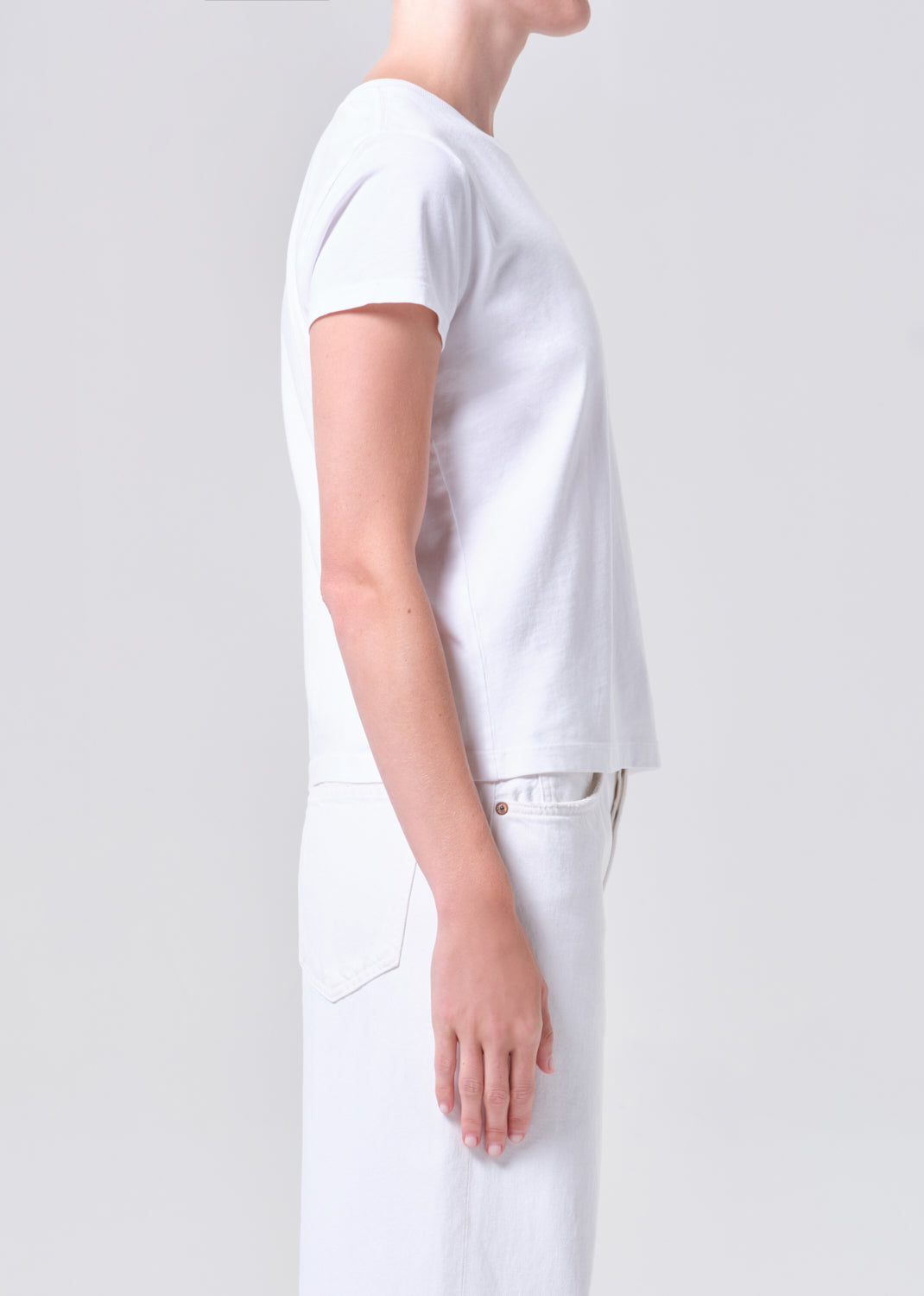 Person wearing a plain white t-shirt and pants on a light gray background