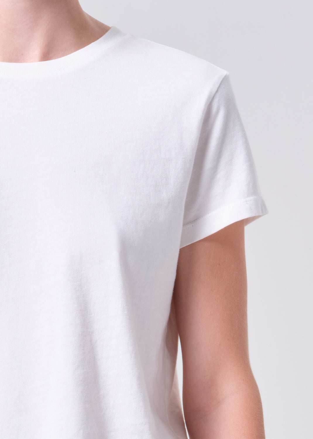 White t-shirt worn by a person on a light gray background