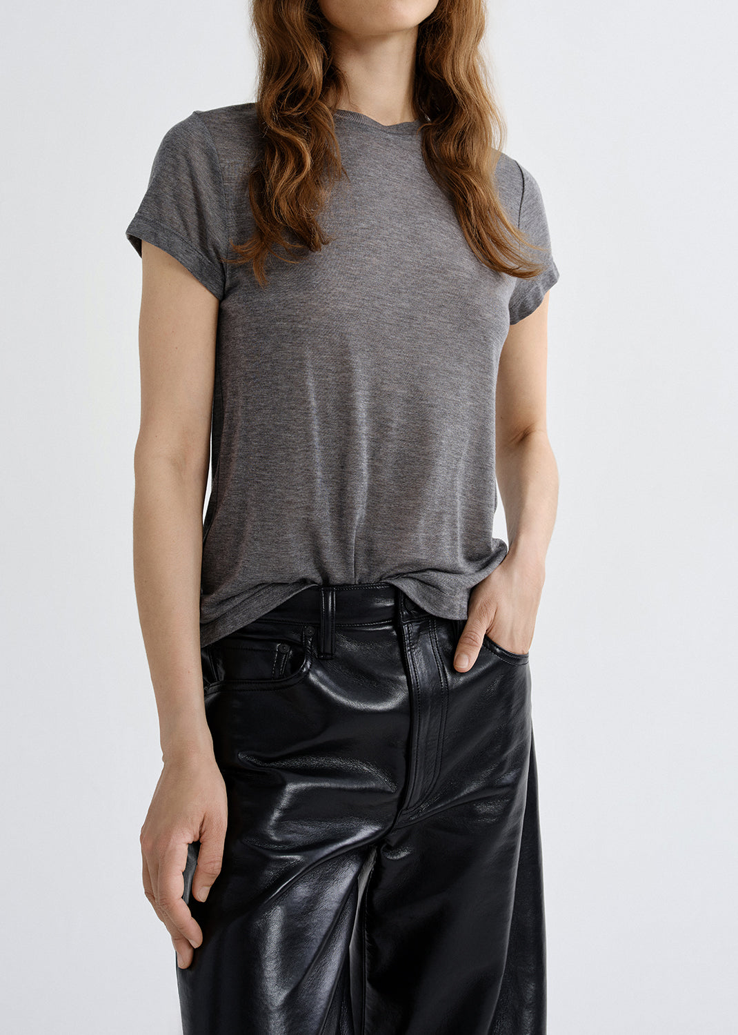 Person wearing a gray t-shirt and black pants on a grey background