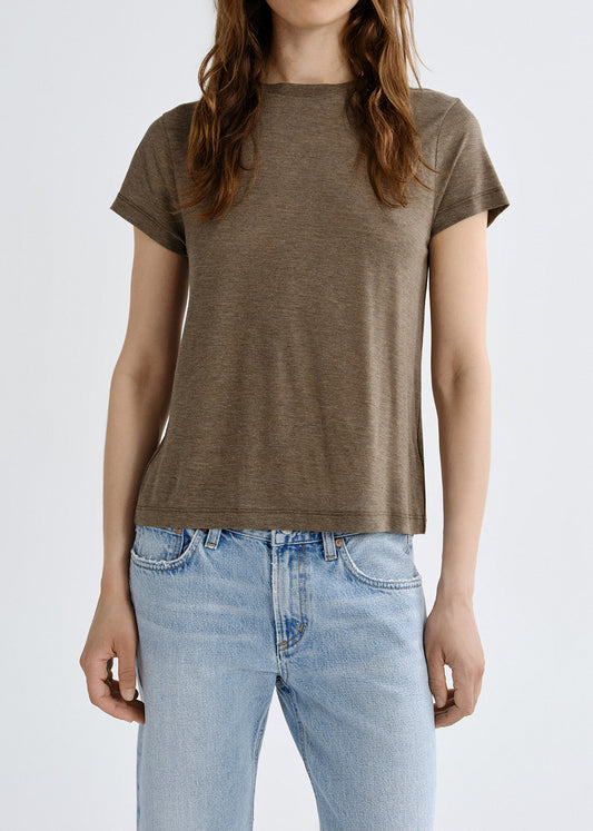Person wearing a brown t-shirt and light blue jeans on a grey background