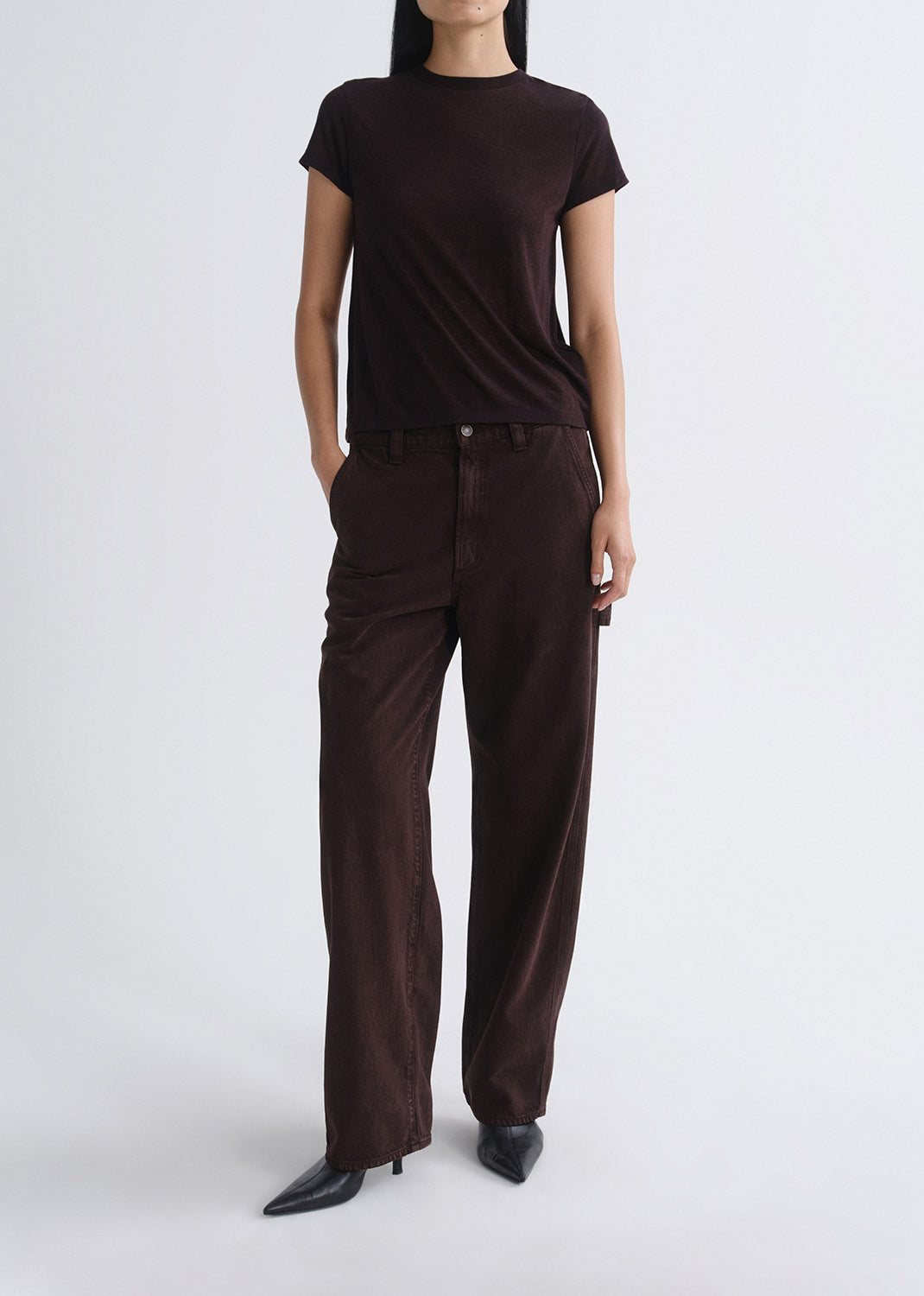 Person wearing a brown t-shirt and wide-leg pants on a grey background