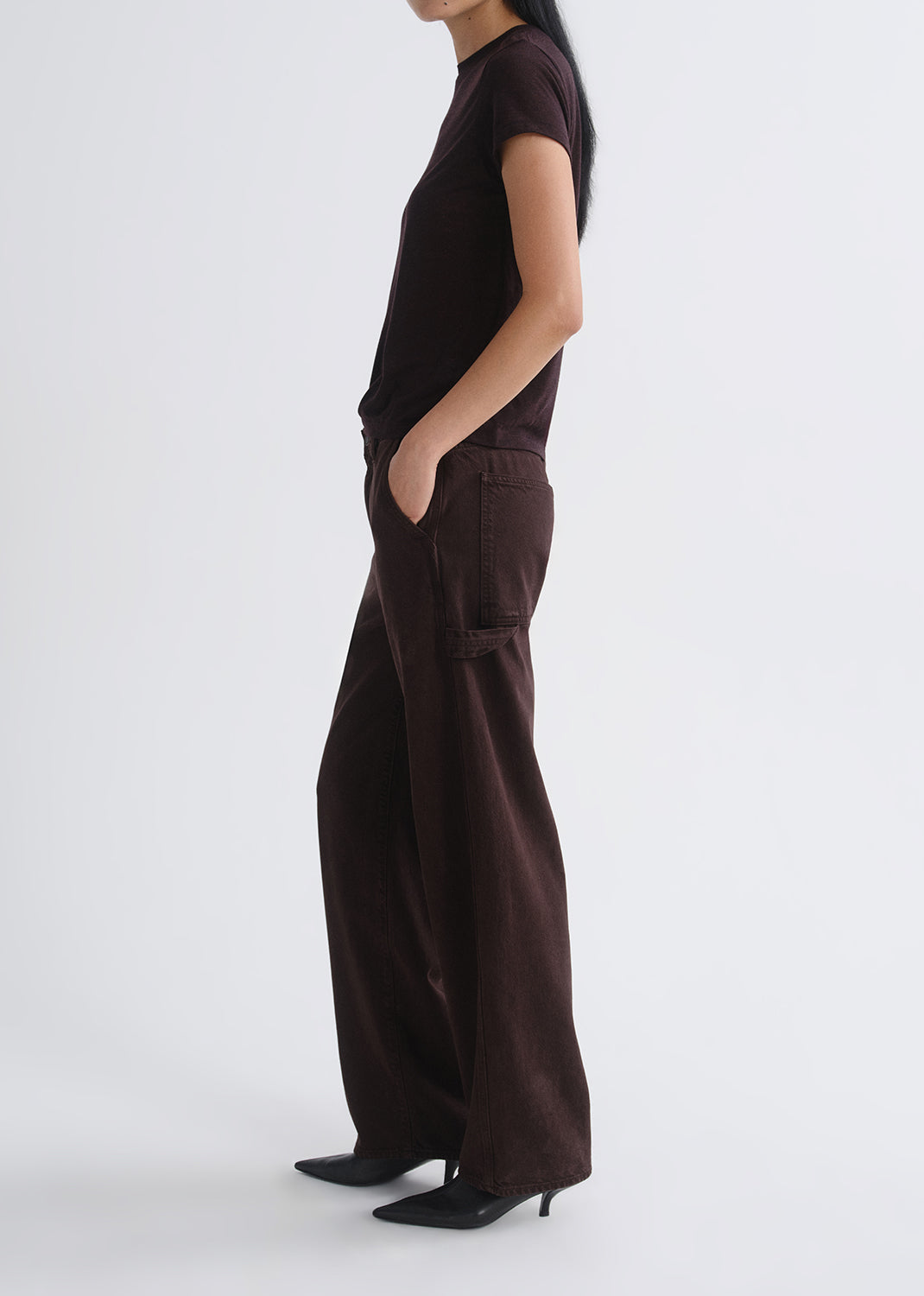 Person wearing brown wide-leg pants and a black top on a grey background