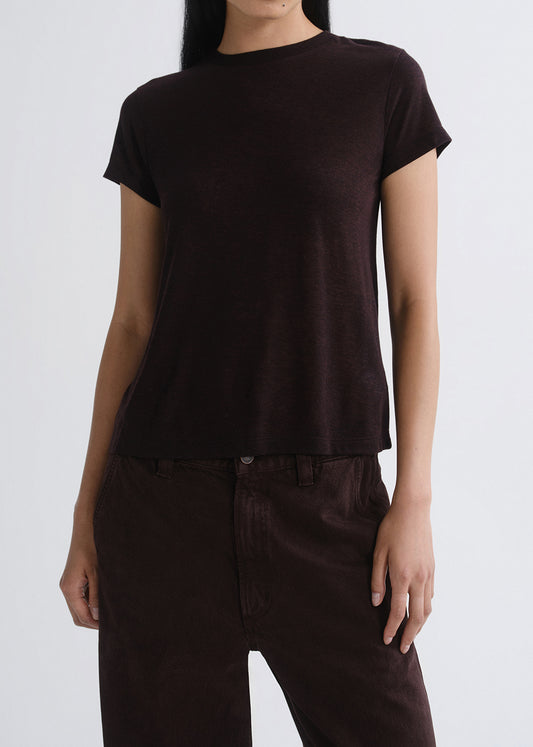 Person wearing a plain black t-shirt and dark pants on a grey background
