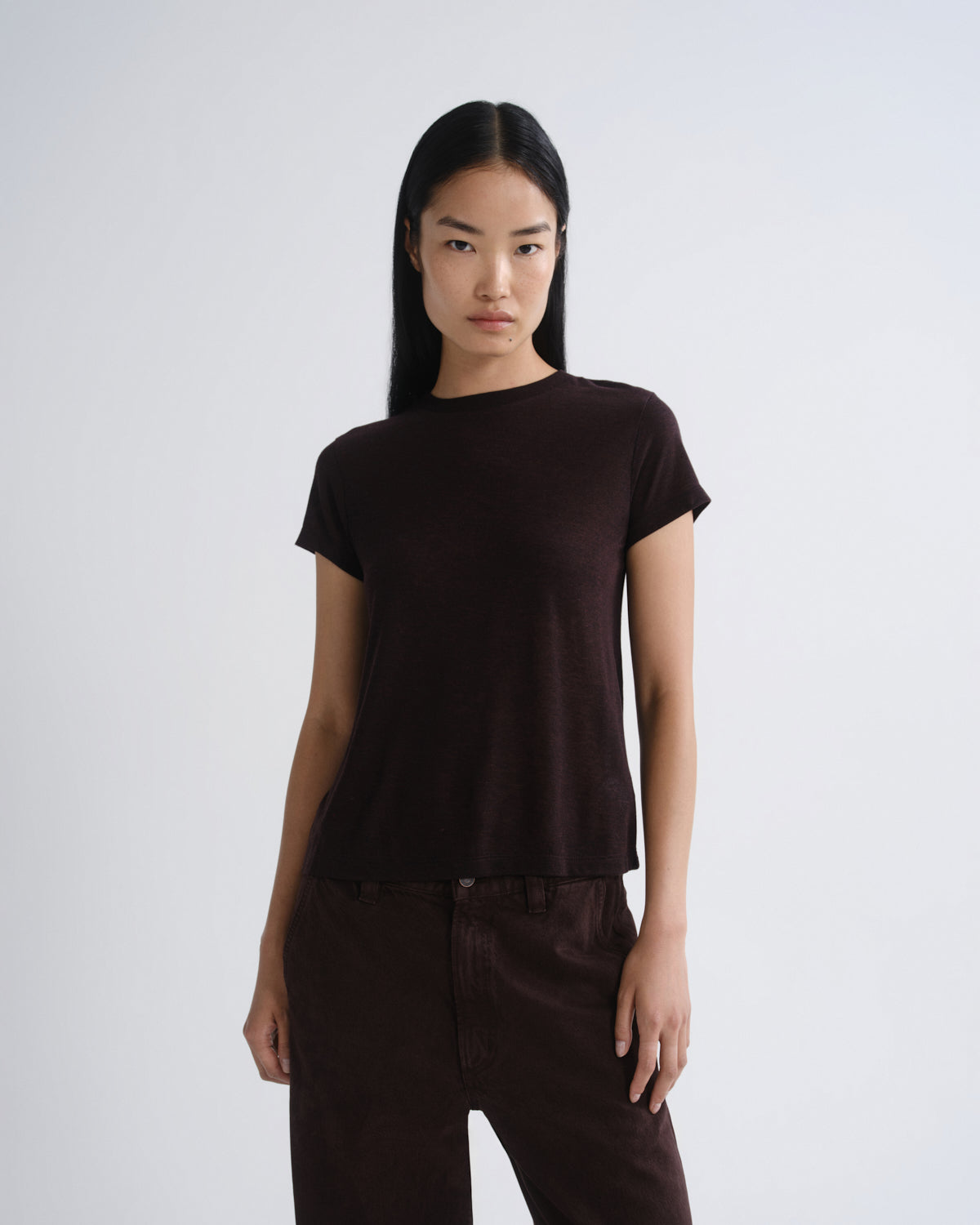 Person wearing a brown t-shirt and pants on a white background