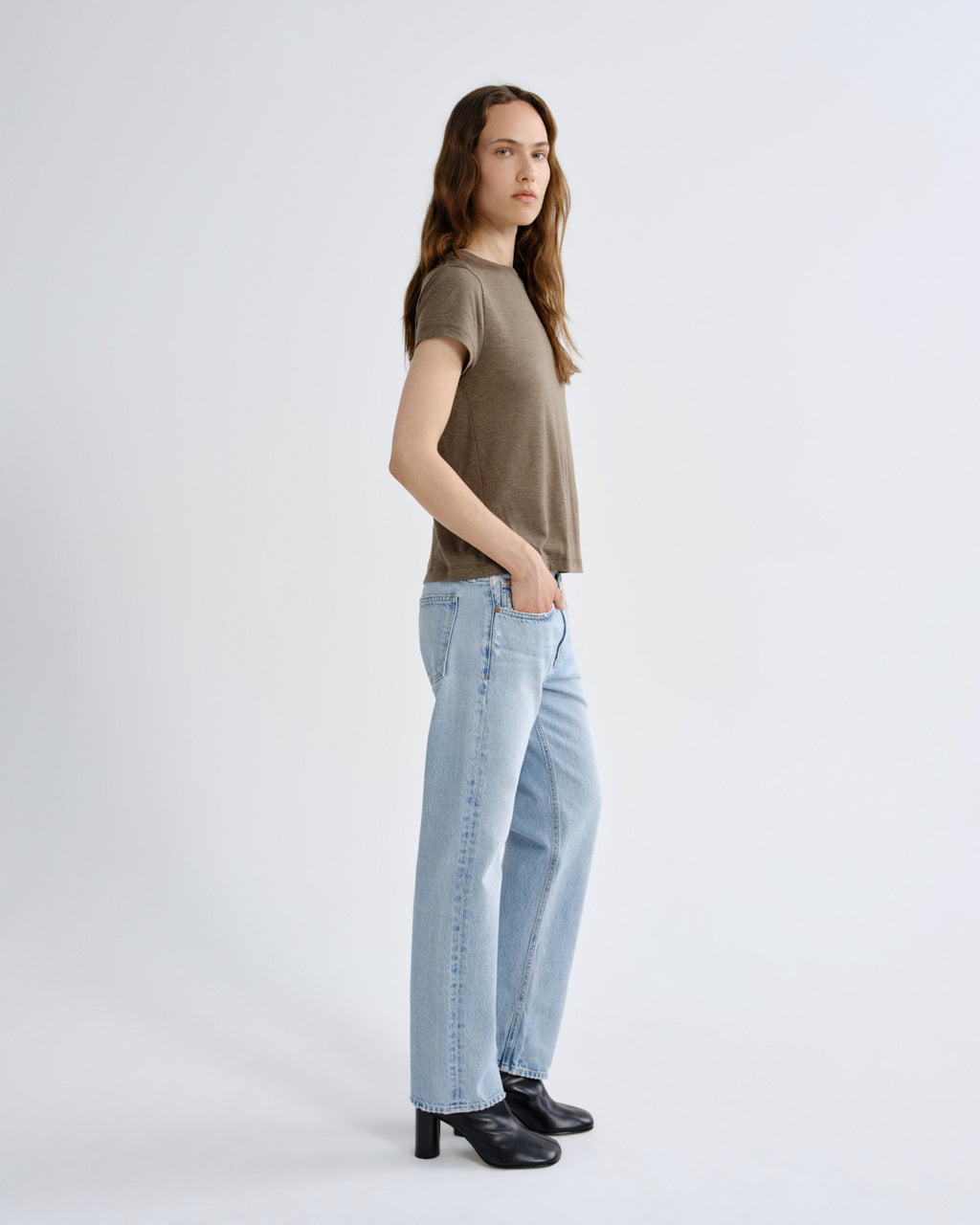 Woman wearing a brown t-shirt and light blue jeans on a white background