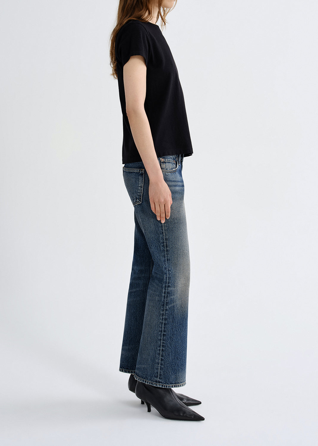 Person wearing a black t-shirt and blue jeans on a grey background