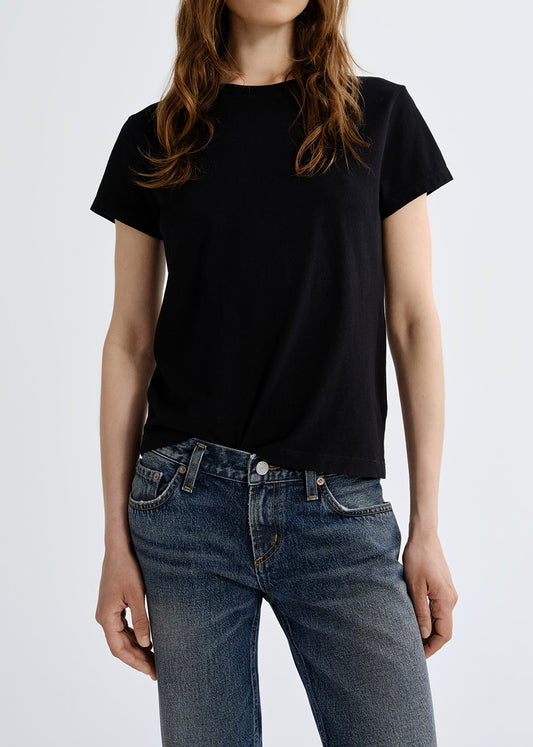 Person wearing a black t-shirt and blue jeans on a grey background