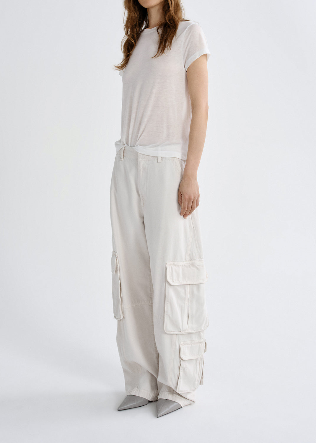 Person wearing a white t-shirt and light-colored cargo pants on a grey background