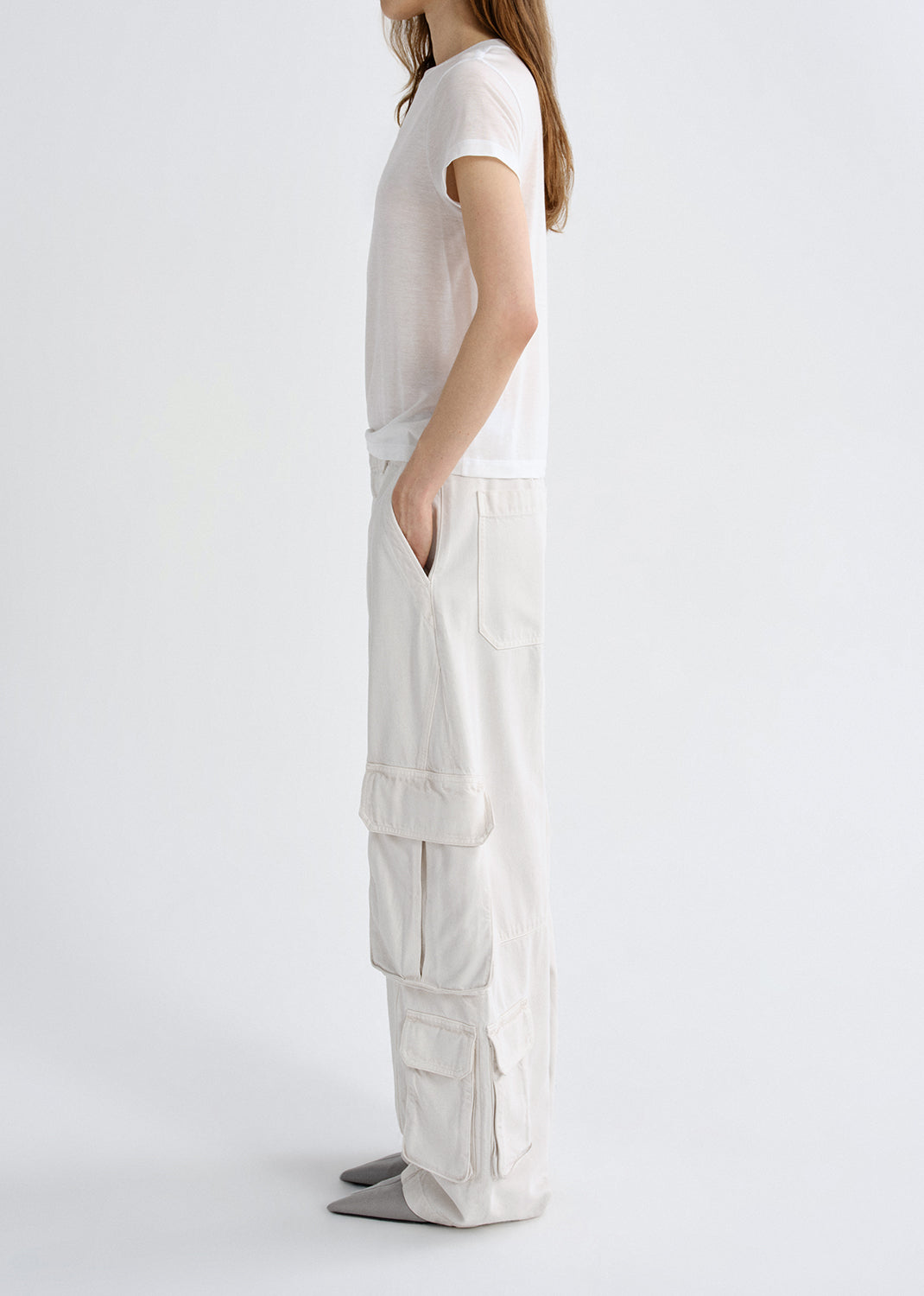 Person wearing a white outfit with cargo pants on a grey background