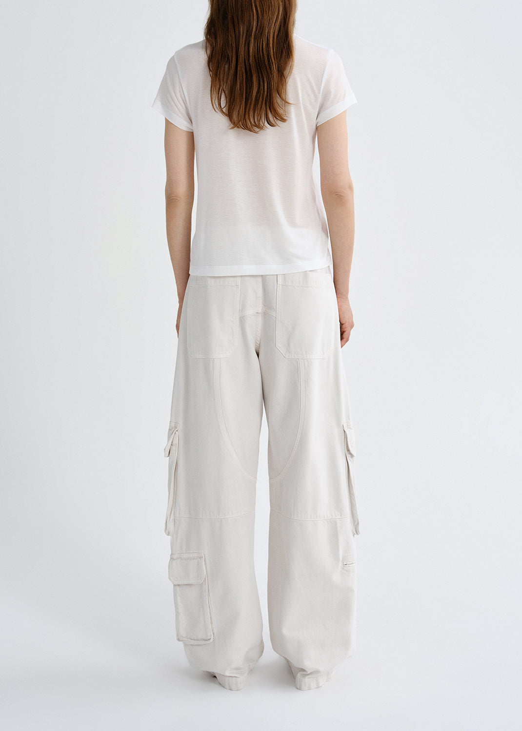Person wearing a white t-shirt and light-colored cargo pants on a grey background