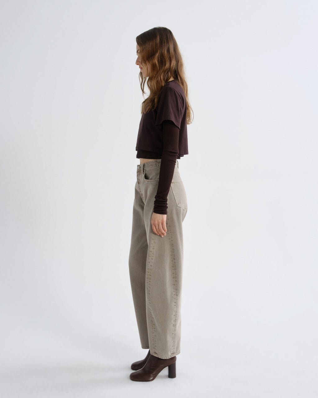 Woman wearing a black top and beige pants on a white background