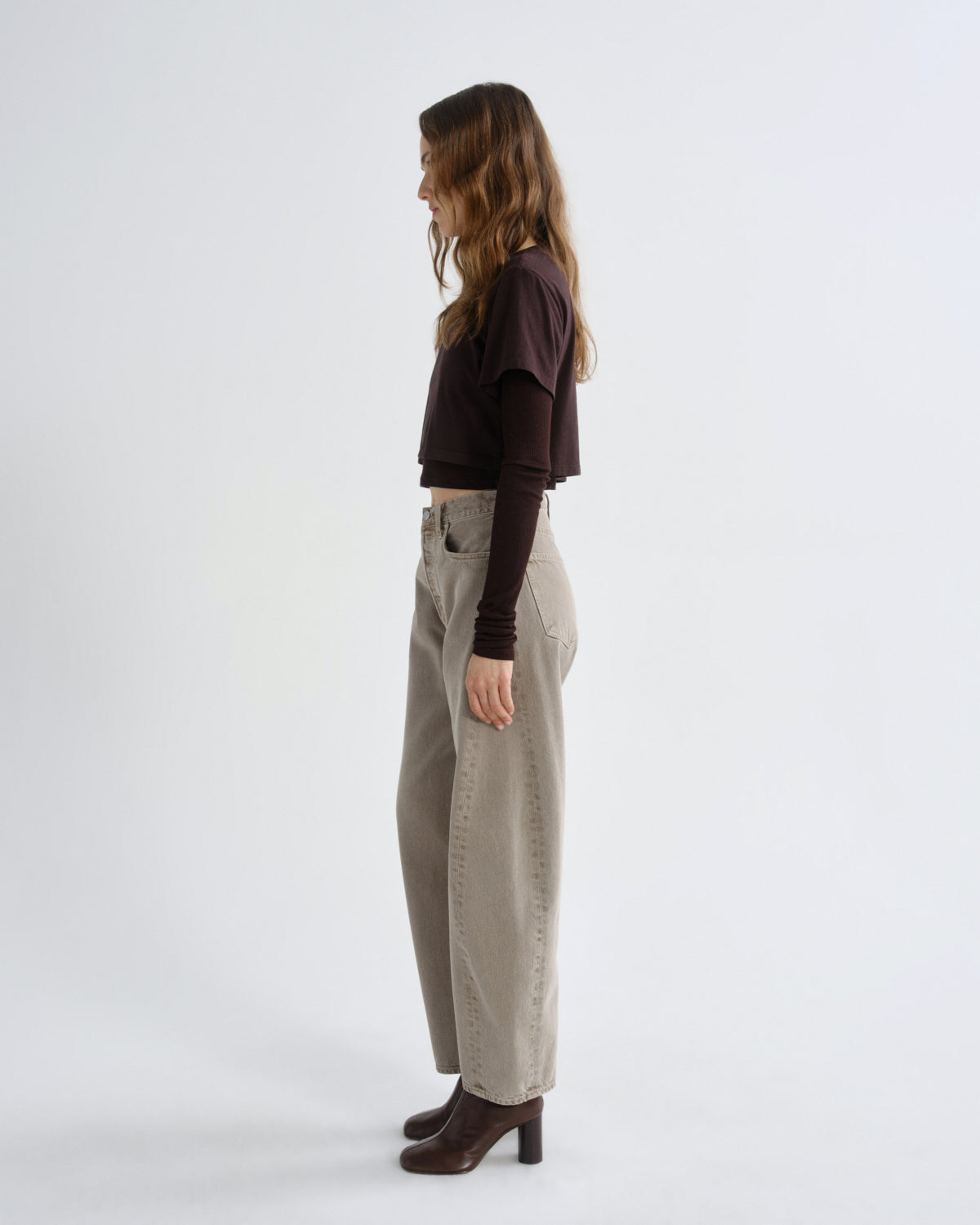 Woman wearing a black top and beige pants on a white background