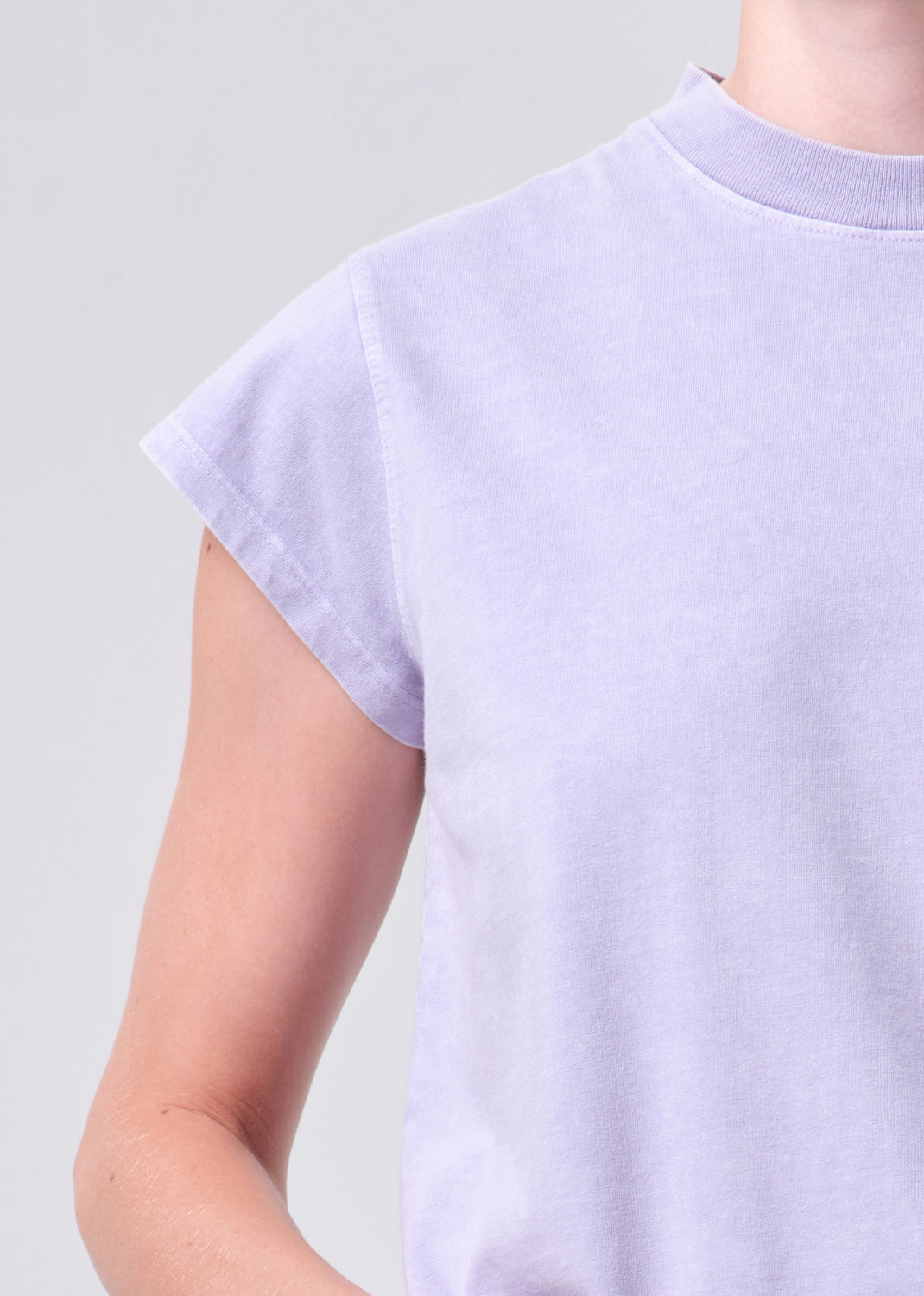 Person wearing a light purple t-shirt against a plain background