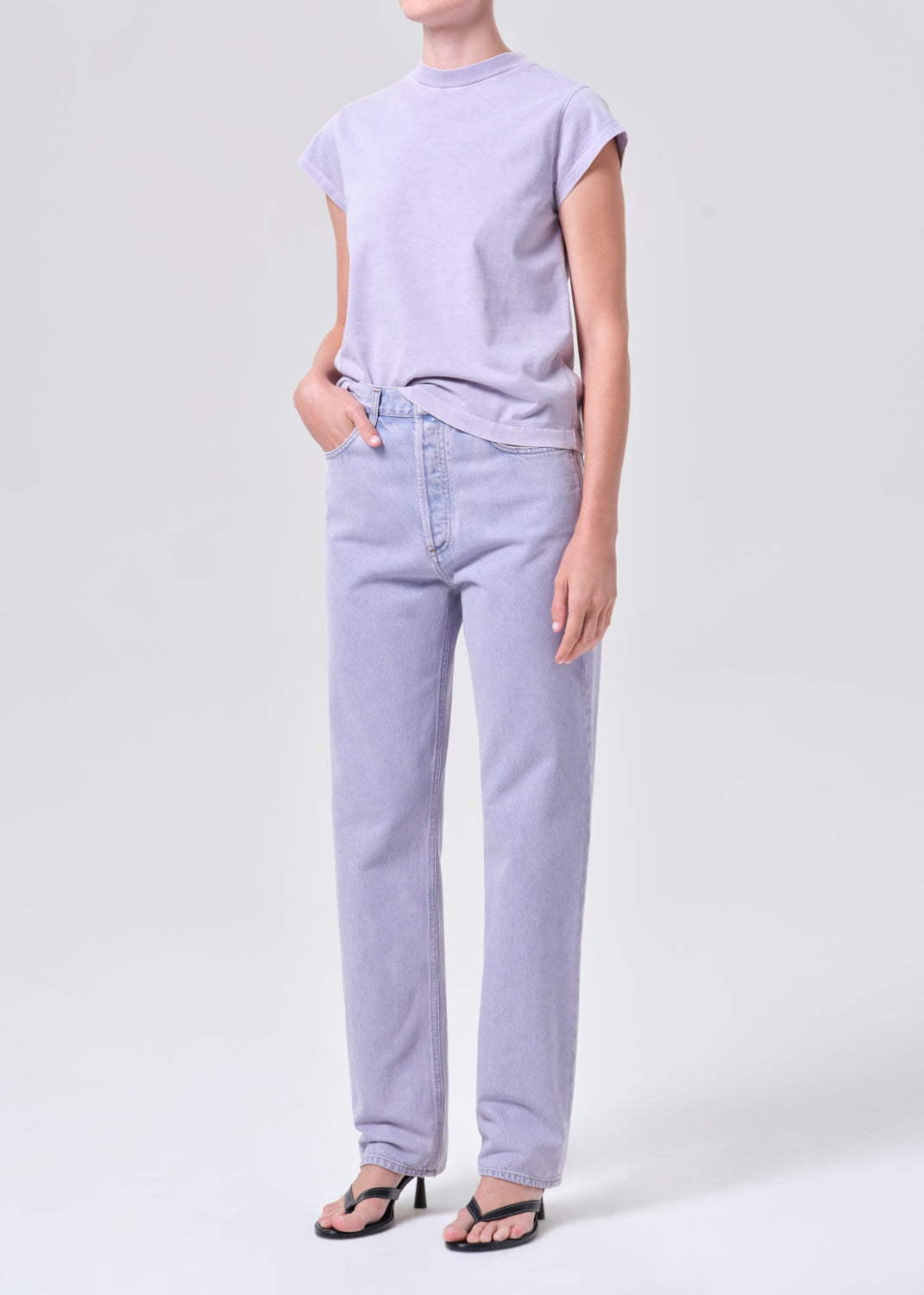 Person wearing a light purple t-shirt and jeans on a white background