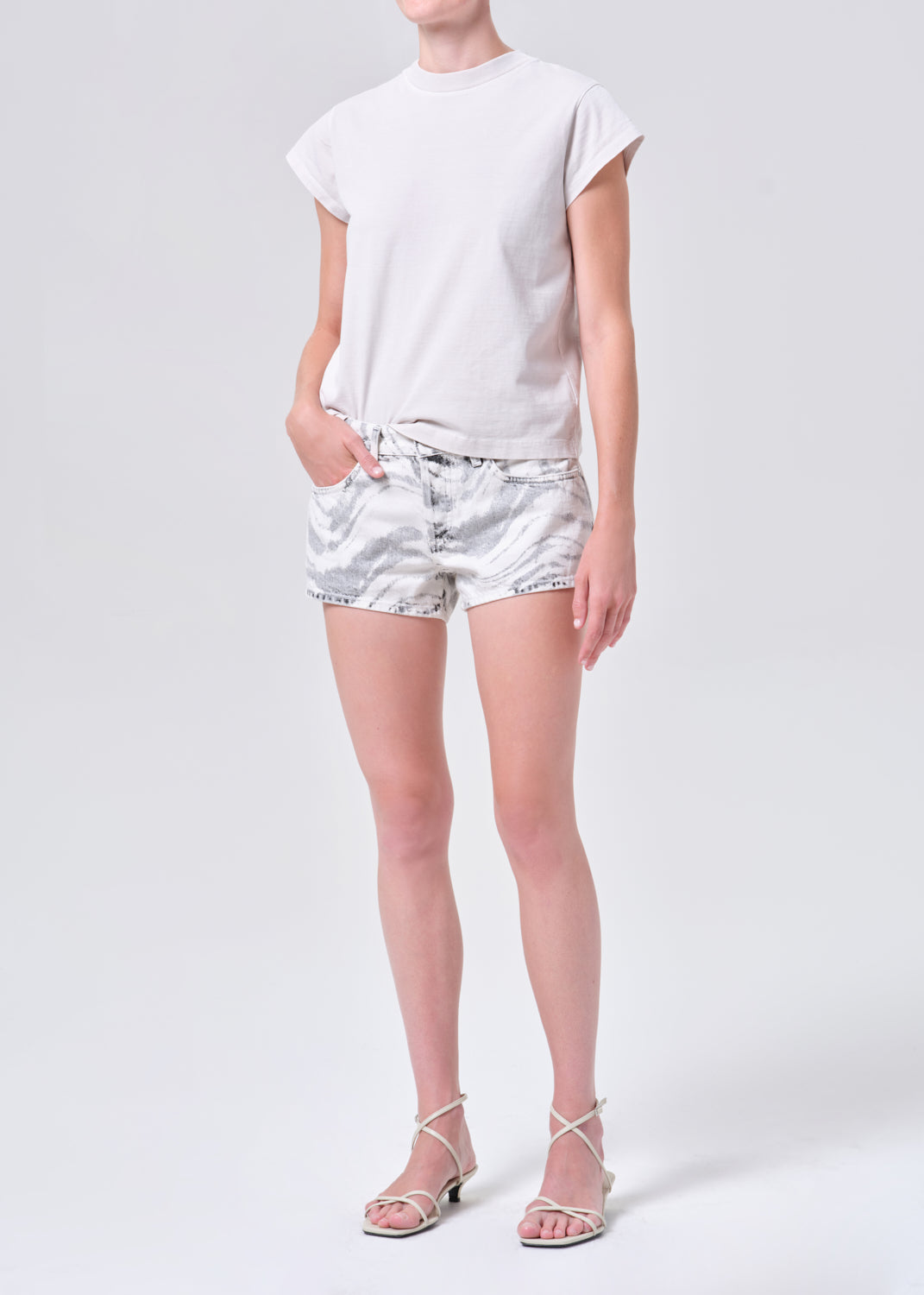 Person wearing a white t-shirt and silver shorts on a white background